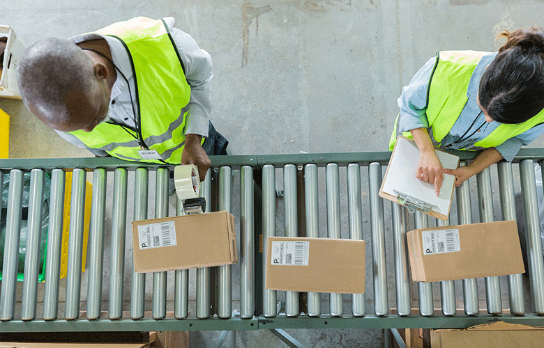 To ansatte ved et samlebånd med pakker som merkes og registreres