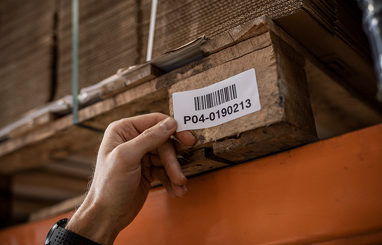 Barcode label being placed on pallet by man's hand