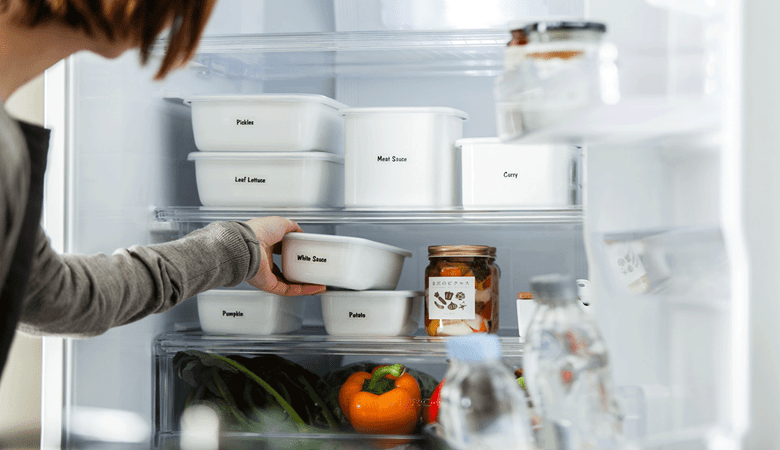 Hvite matbeholdere som er merket med sorte Brother P-touch merketape plassert i et kjøleskap