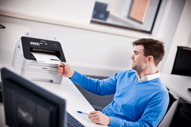 mand sidder ved skrivebord fax