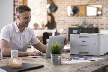 Man sitting at desk with printer nearby