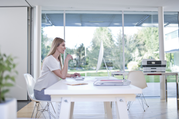 Woman sitting at white table with printer in background