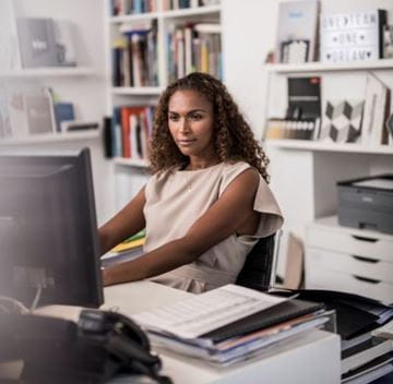 Kvinde i kontormiljø, der arbejder ved en computer