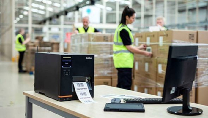 TJ labelprinter på lager med kvinde i baggrunden