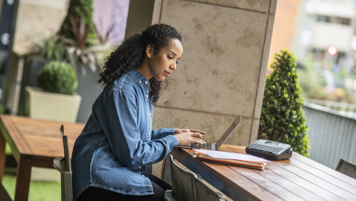 woman sitting at a table with laptop, next to Brother printer