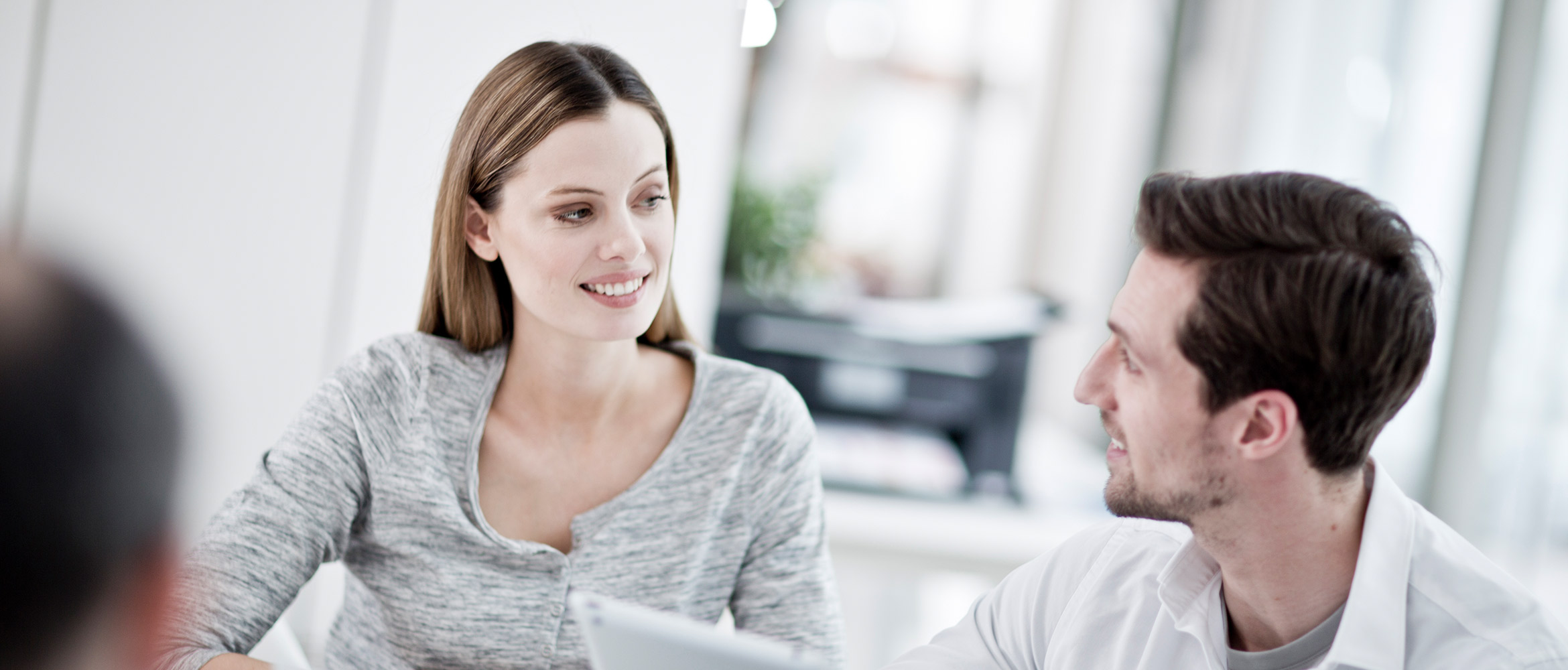Homem e mulher na frente do laptop estão sorrindo, impressora em segundo plano