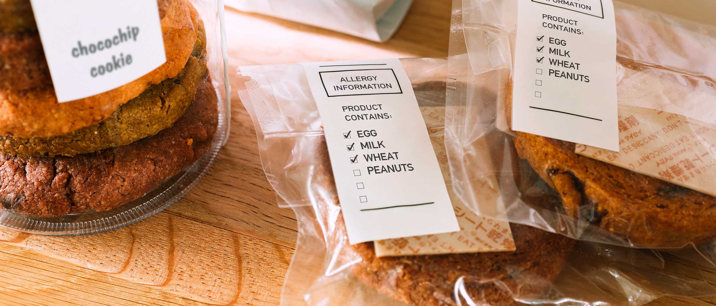 Cookies in a glass jar with white and black label, two packs of cookies in plastic bags with white and black label