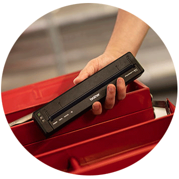 Person holding Brother PJ-7 compact printer in front of a red metal box