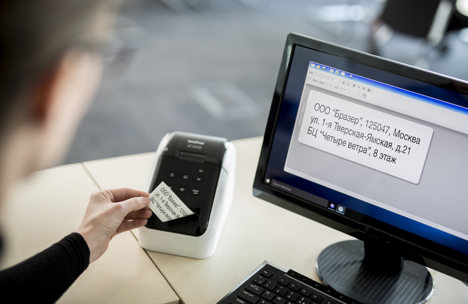 An office worker removes a printed label from their QL label printer 