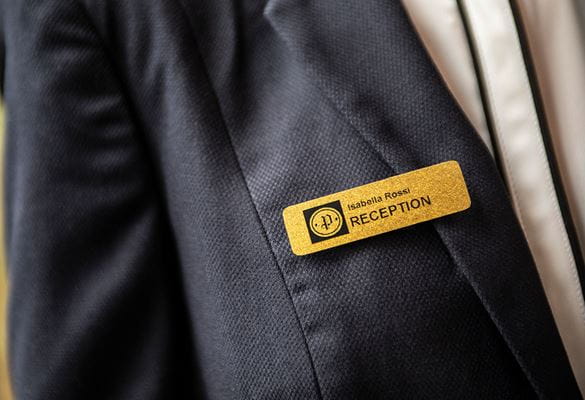 Gold glittery staff identification badge on a grey suit jacket