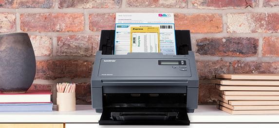 Brother PDS-6000 professional scanner scanning a document, brick wall, vase, note books