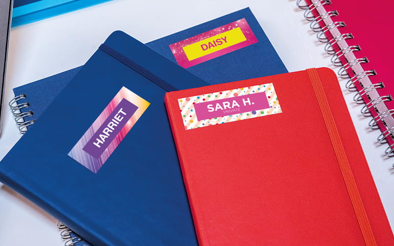 Pile of 2 blue books and 1 red book with colourful name labels on them