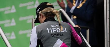 The back of cyclist Leah Dixon while she's climbing steps up to a podium