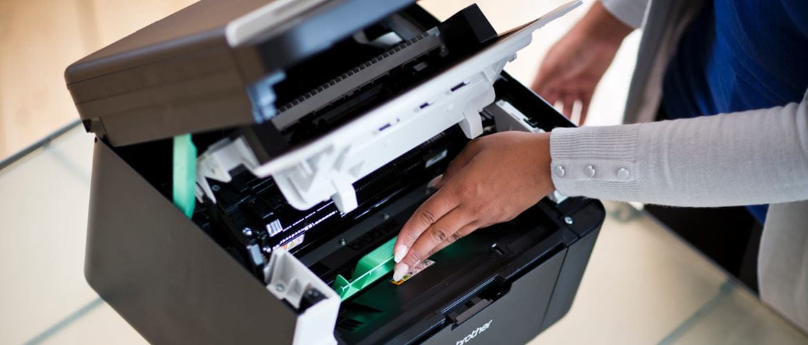 A lady inserting a toner cartridge into a laser printer, revealing the inner workings