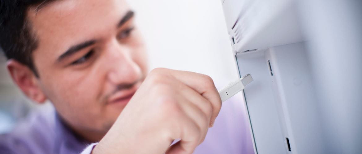 A man inserting a network cable into an ethernet port on the back of a printer
