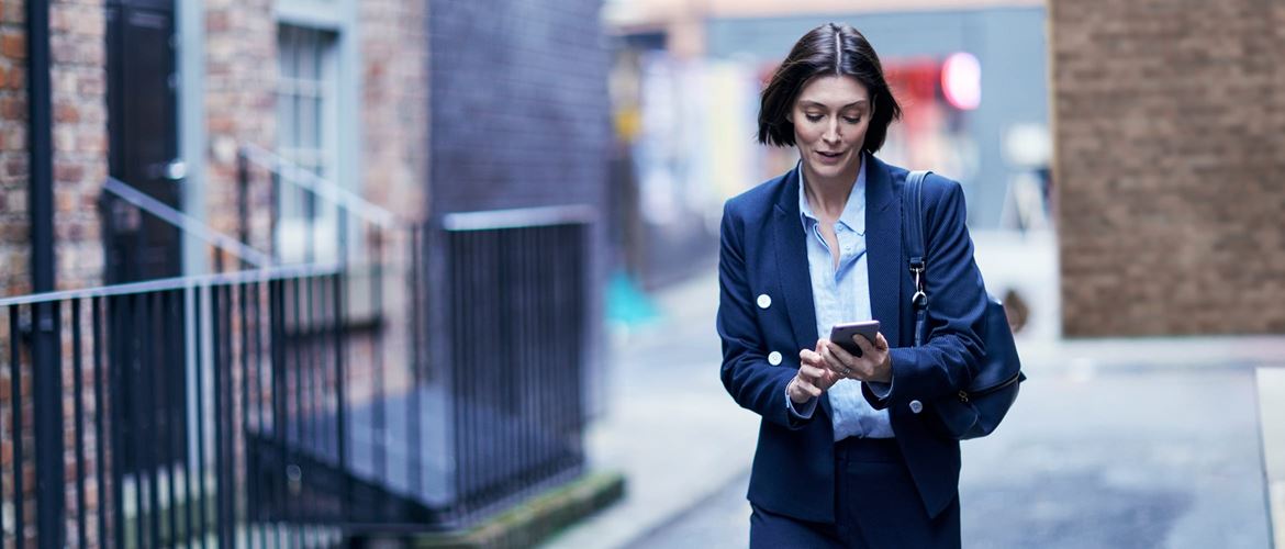 A woman looking at her smartphone while walking down a street