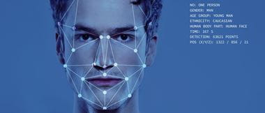 Facial recognition graphical outline superimposed onto a young mans face with his statistics displayed on a blue background