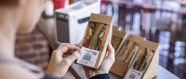 A caterer applying a label to sandwich packaging which includes information about food allergy ingredients