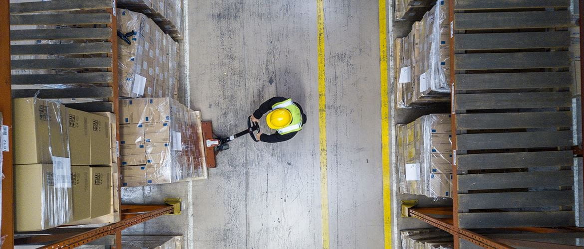 A warehouse worker in a hard hat loading up some boxes