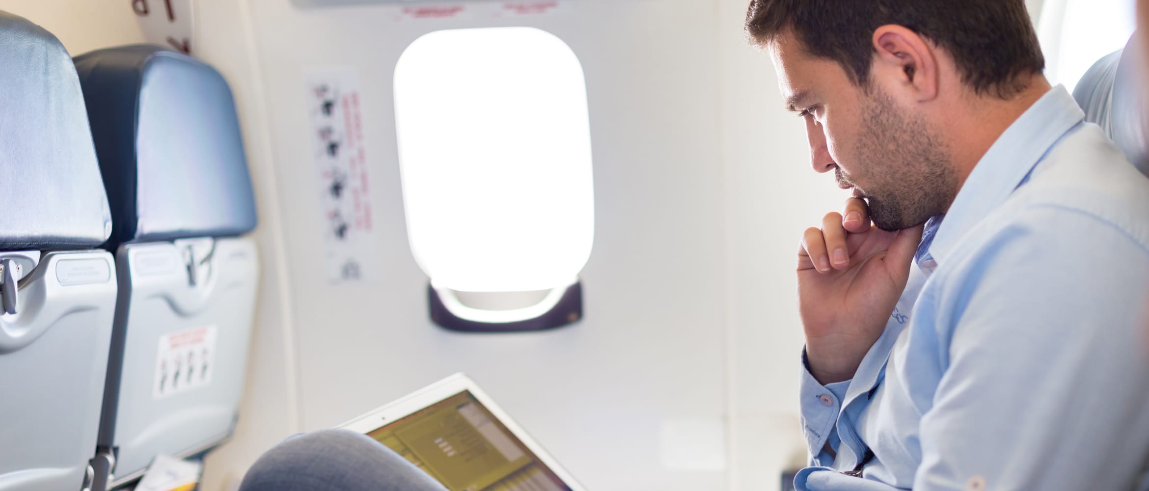 Gentleman sat on a plane using a laptop