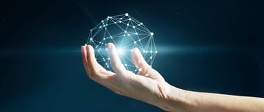 Hand holds a geometric glowing globe to illustrate the responsibility of change management, particularly within the NHS