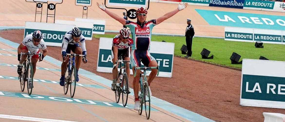 Cyclist Magnus Backstedt crossing the finish line with his arms in the air at Paris-Roubaix