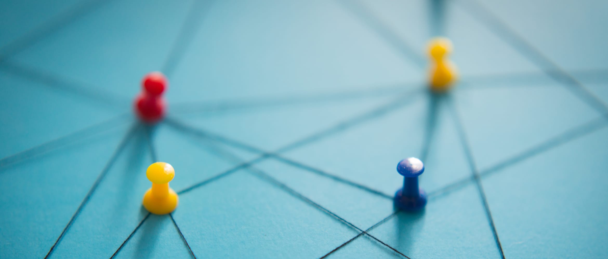 Red, yellow and blue pins on a light blue board, connected by black threat to represent a network