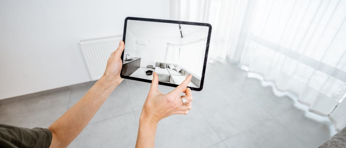 A person in an empty room using an augmented reality app on a tablet device to make interior design decisions