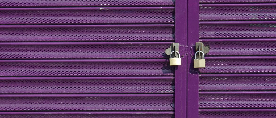 Two padlocks on purple retail store shutters