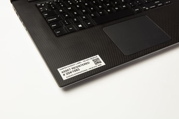 A black on white QR code asset tag applied to the bottom left palm rest of a black notebook computer