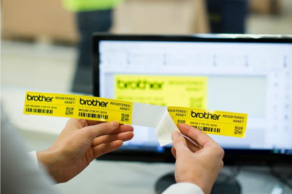 A lady peeling a QR code asset label from a long yellow tape with Brother’s P-touch editor software in the background