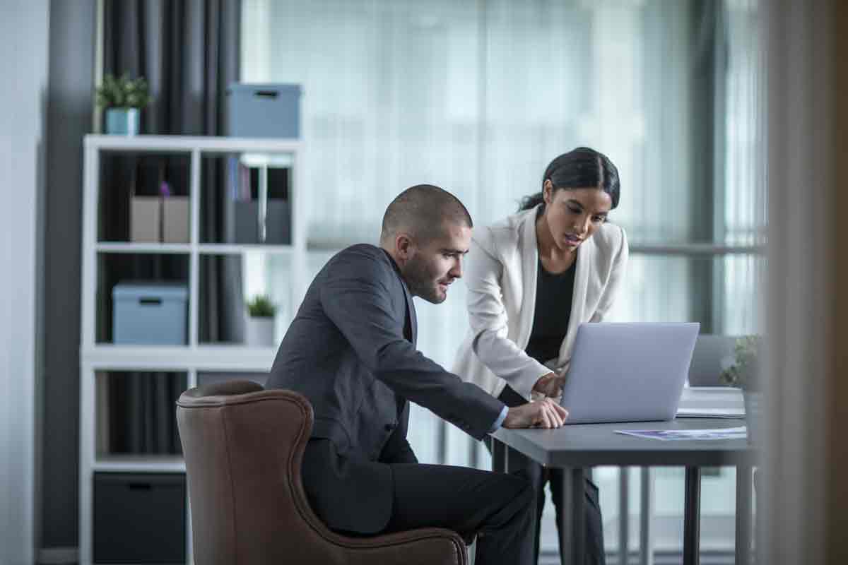 A lady and gentleman sat at a table looking at a laptop