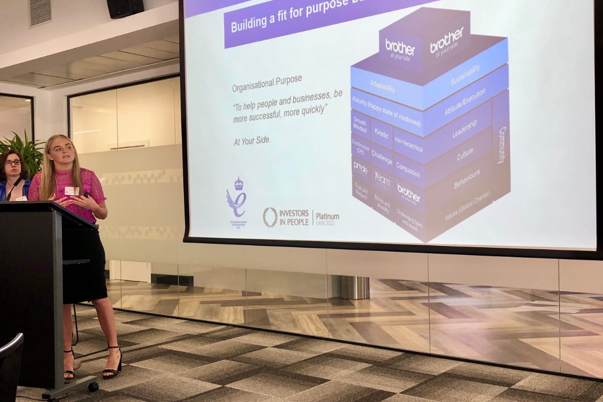 Sustainable Development Coordinator, Gemmer Crozier presenting at a conference with a projected image of 'Building a fit for purpose business' illustration