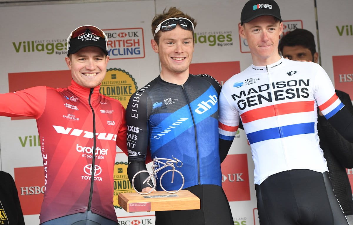 Three male racing cyclists, podium, smiling