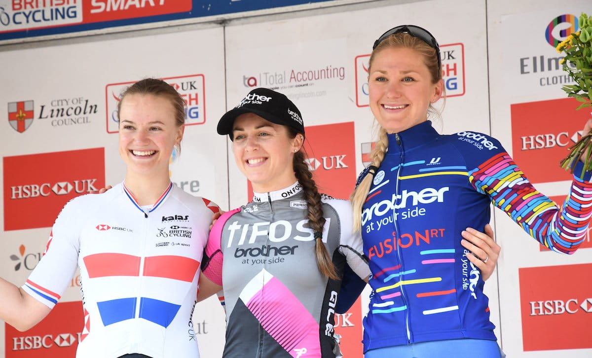 Three female racing cyclists, podium, smiling