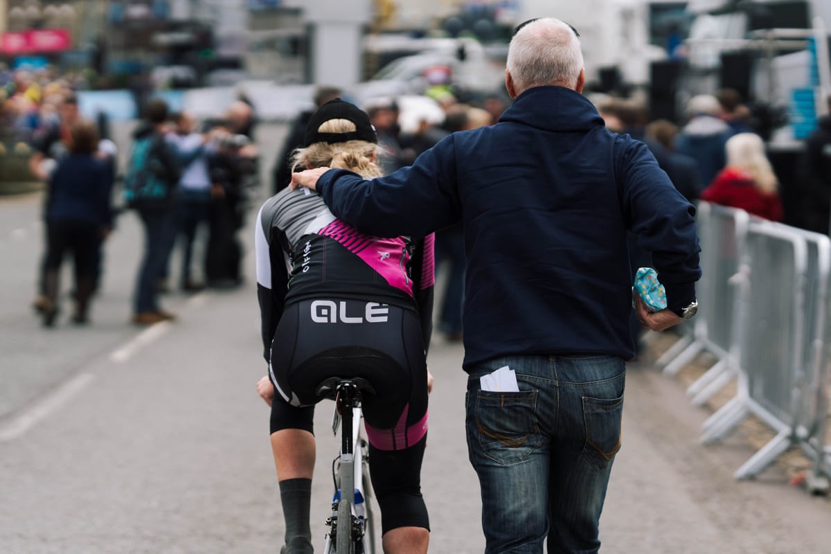 Brother UK-Tifosi p/b OnForm cyclist riding away with support team member's hand on her shoulder