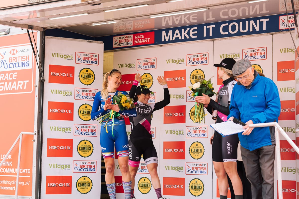 Cyclists Anna Henderson, Rebecca Durrell and Leah Dixon celebrating on a podium after a race