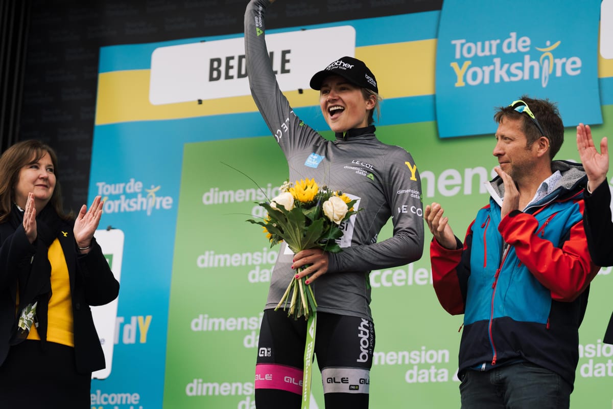 Cyclist Leah Dixon cheering to spectators after receiving a bouquet of flowers at the Tour de Yorkshire race