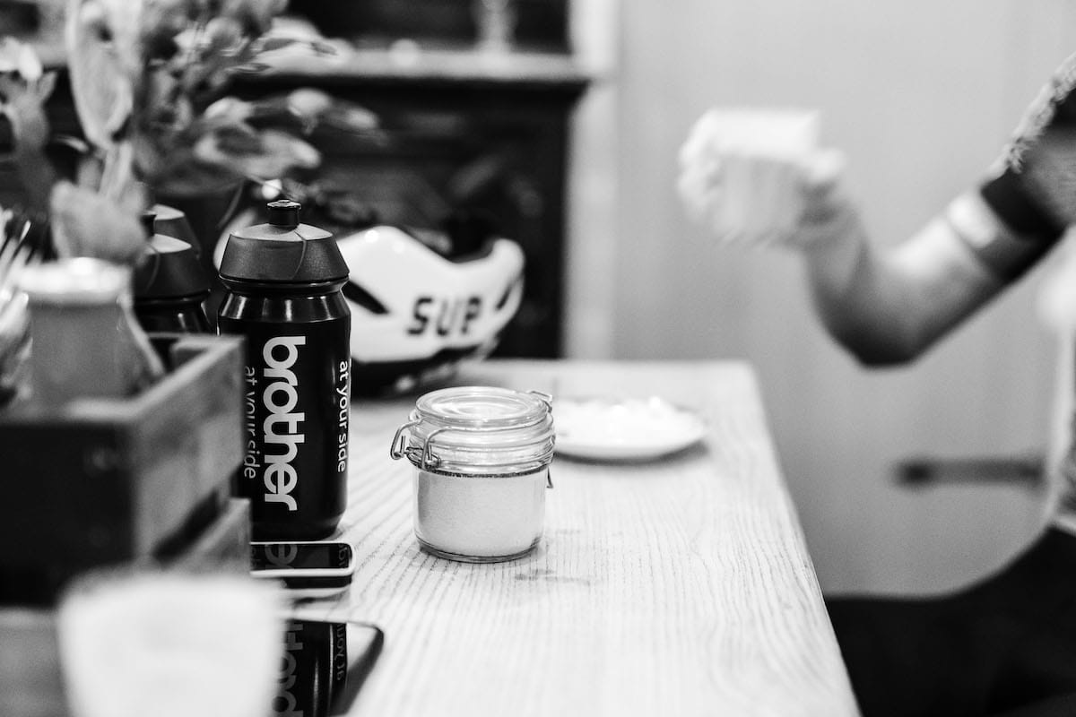 Black and white photo of a close up of a brother branded cycling bottle in a coffee shop