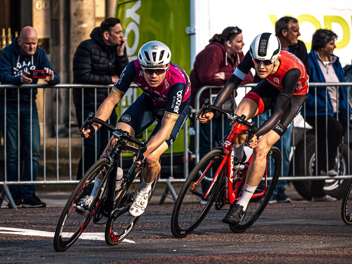 Two cyclists turning a corner as the pass spectators