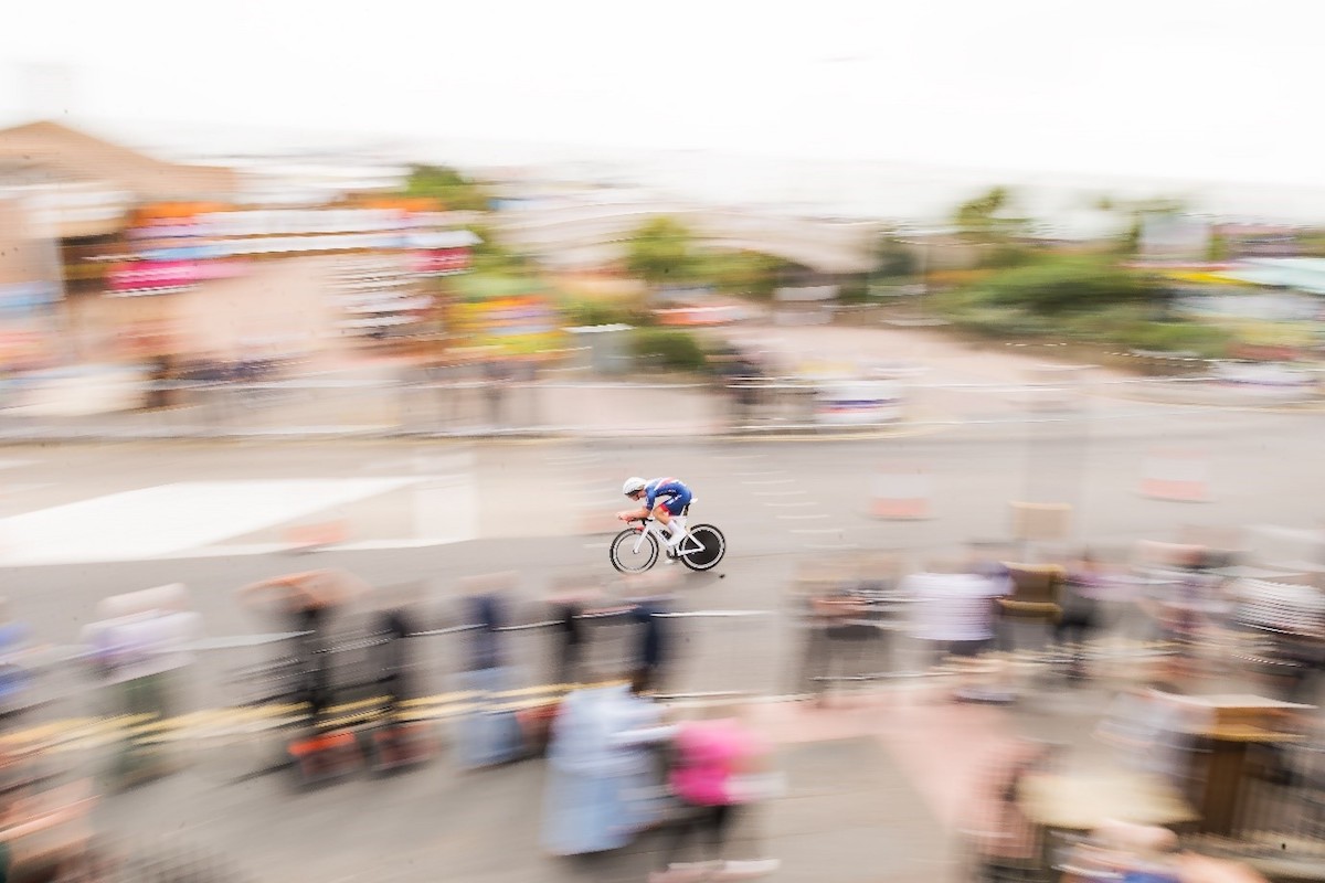a cyclists passes supporters at speed