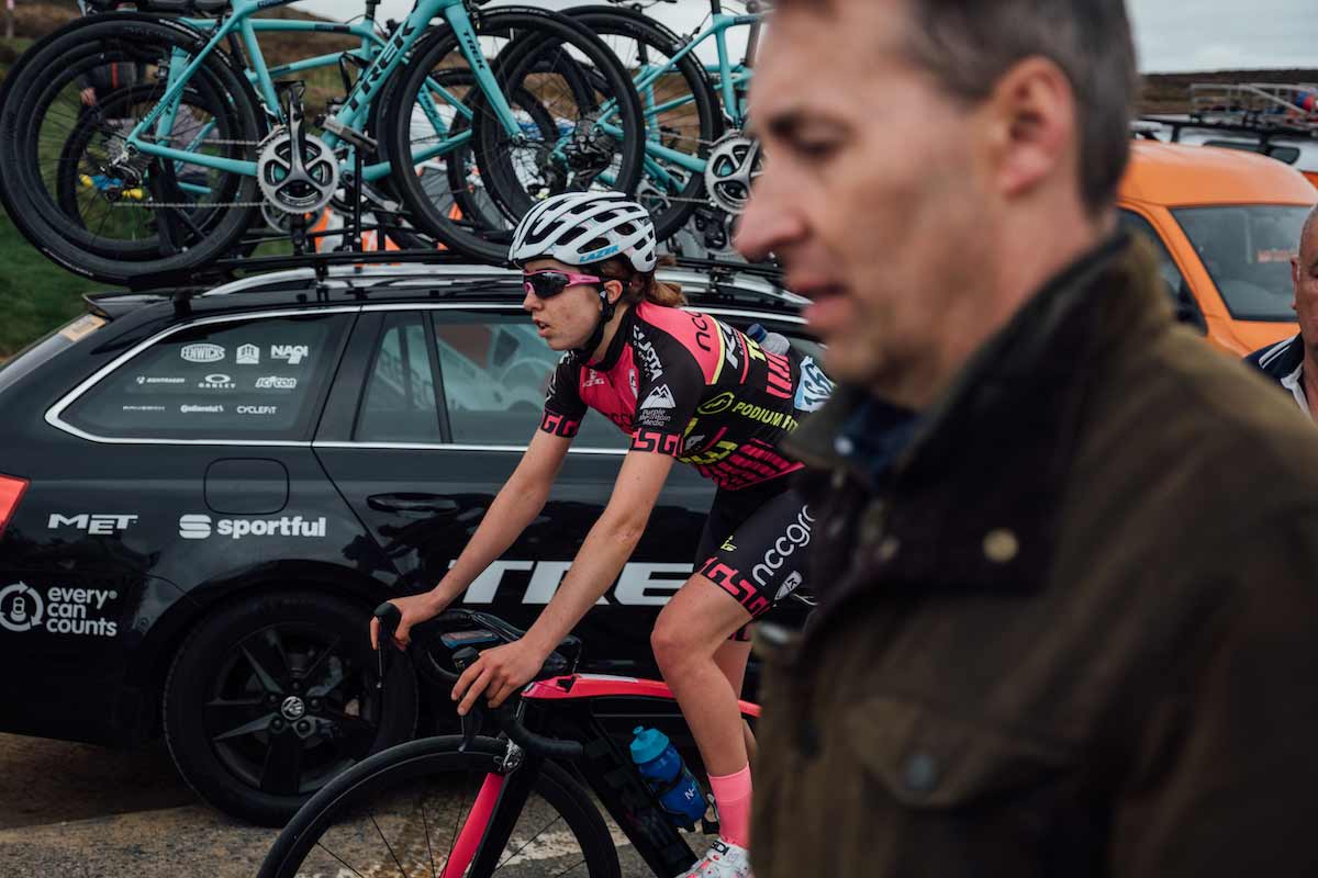 Sophie Wright cycling past a support car