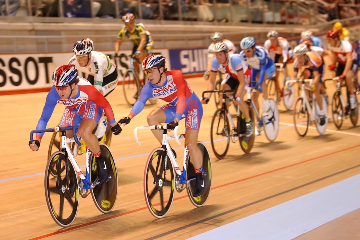 Brothers Dean and Russell Downing leading a group of cyclists at a velodrome with spectators in the background