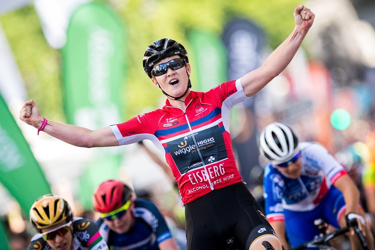 cyclist wins race stage and celebrates with arms in the arm