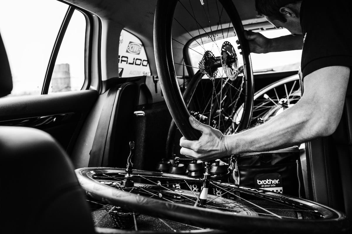 A member of the Neutral Service support crew holding a bike disc wheel in the back of a race support vehicle
