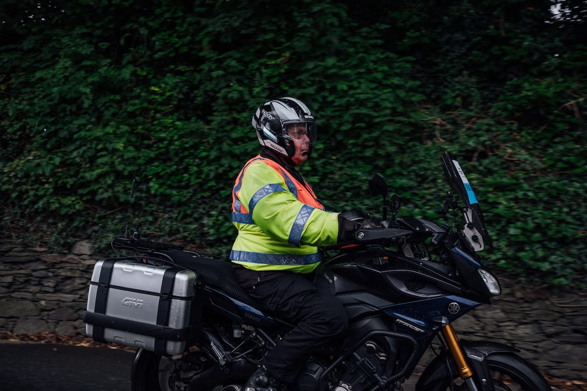 Side view of a motorcyclist wearing a high visibility jacket as he's riding past