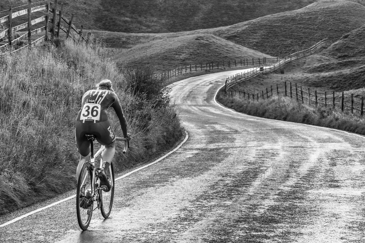 Cyclist Lizzie Banks riding down a winding hilly road