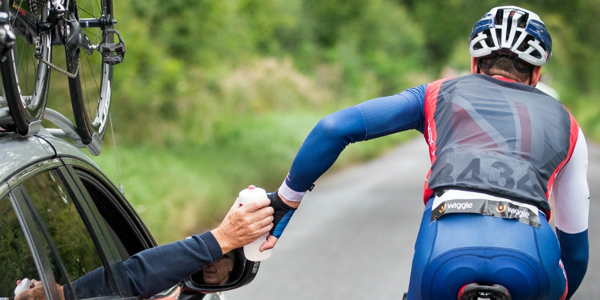 cyclist takes on water from support vehicle