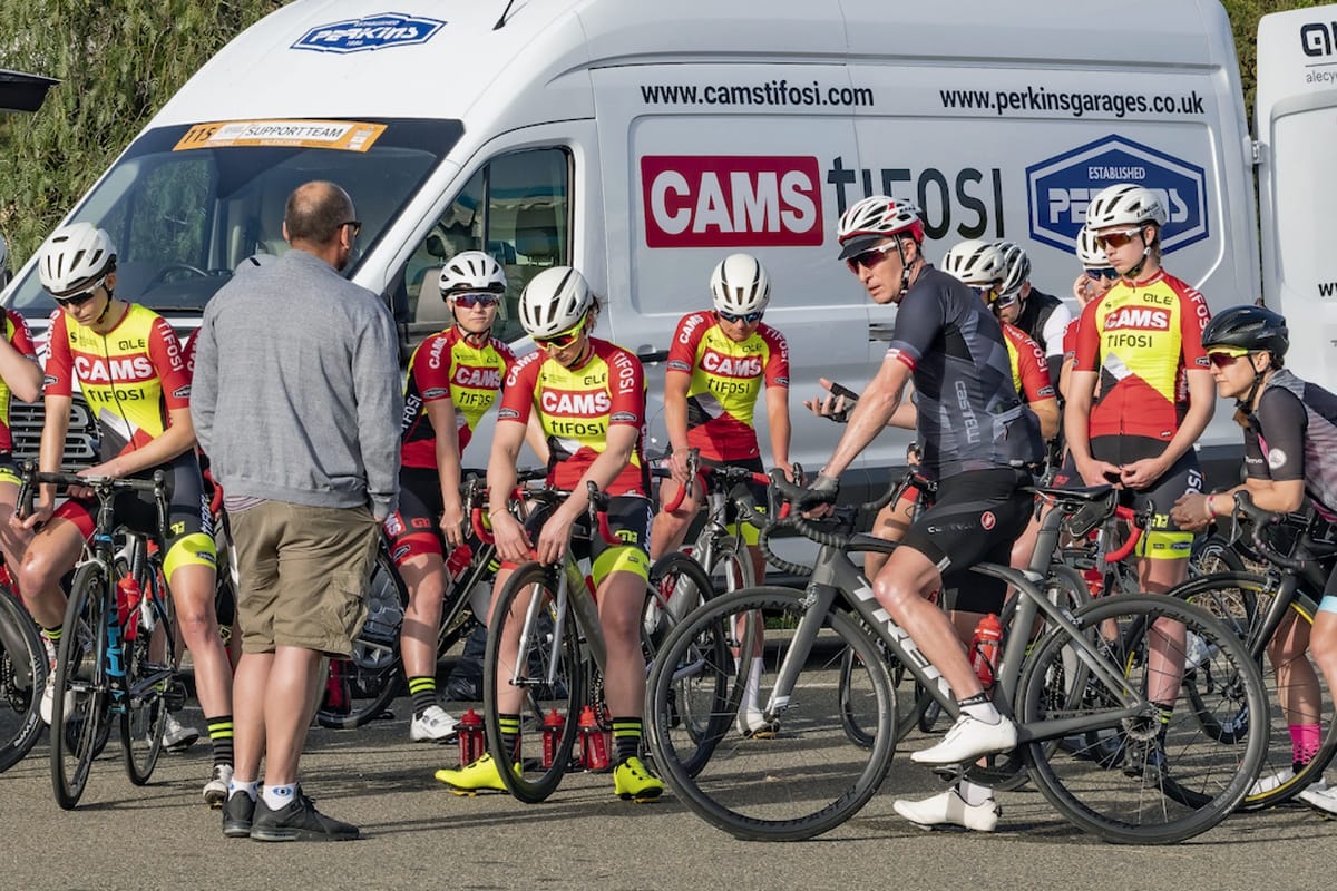 Chartered psychologist Peter Hudson advising the CAMS-Tifosi team who are straddling their bikes in front of a support vehicle
