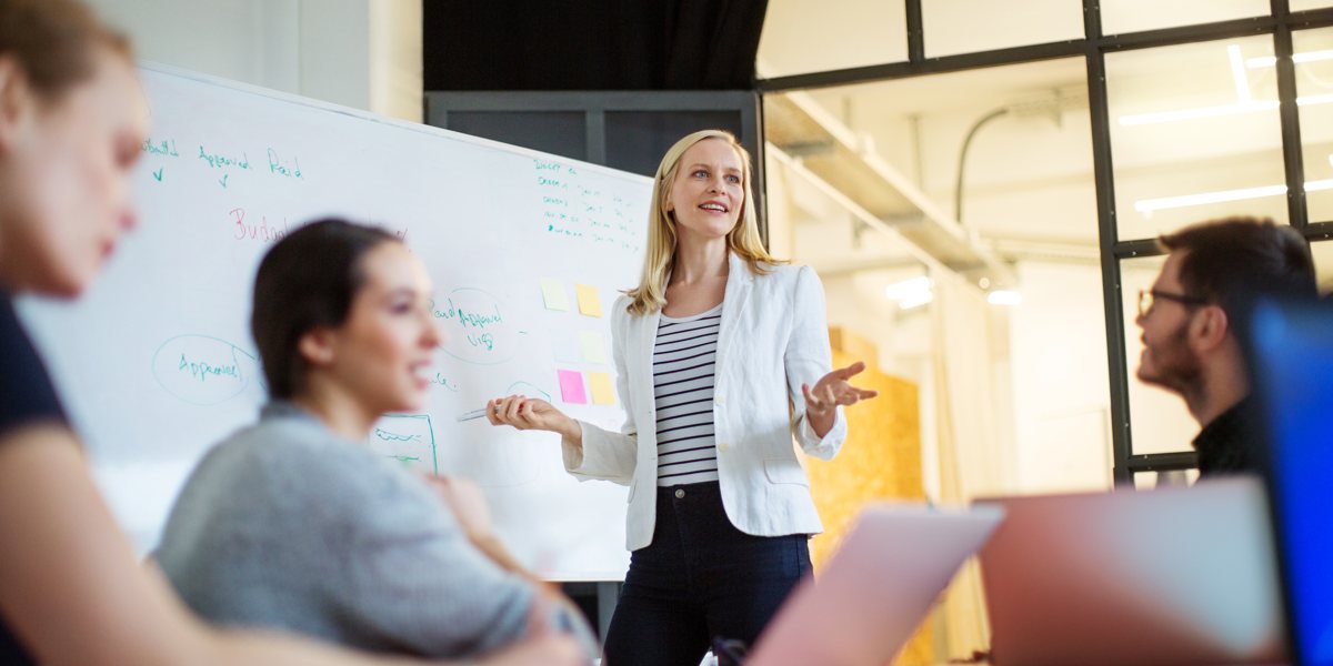 SMB business meeting being chaired by a woman in front of a whiteboard